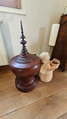 une table en bois sur laquelle est posé un vase, à côté d'un lit