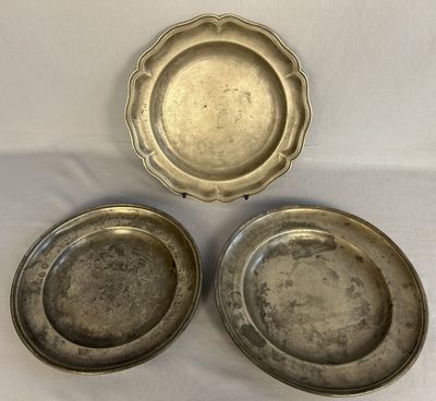 trois assiettes en métal argenté posées sur une nappe blanche