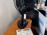 un ventilateur posé sur un bureau en bois à côté d'un ordinateur