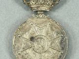 silver medal with blue ribbon and crown on grey surface