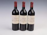three bottles of red wine sitting next to each other on a white surface