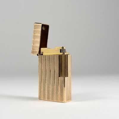 un gros plan d'un briquet doré posé sur une surface blanche