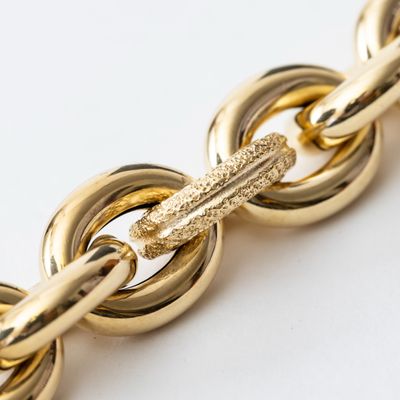 a close up of a gold chain on a white surface