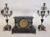 three candles and a clock sitting on a table