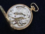 an antique pocket watch on a black cloth with a gold chain