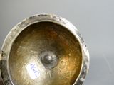 a silver vase sitting on a table with a sticker on it