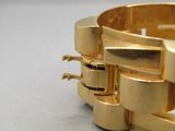 gros plan d'un bracelet en or sur une table
