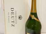 La bouteille de champagne se trouve à côté de la caisse de vin.