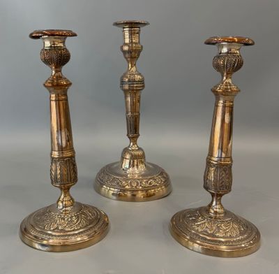 trois bougeoirs anciens en laiton sur fond blanc