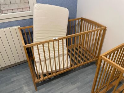 a baby crib with a mattress and a wooden crib