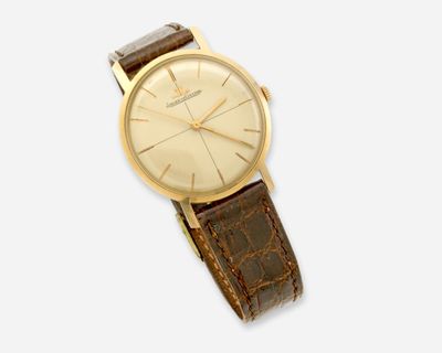 gros plan d'une montre sur une surface blanche avec un bracelet marron