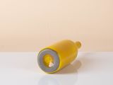 a close up of a yellow bottle on a table with a white surface