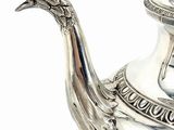 a silver tea pot with a peacock on it