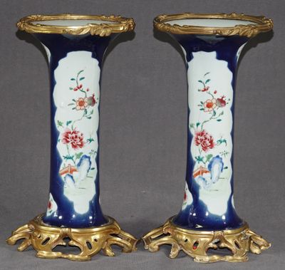 une paire de vases bleus et dorés ornés de fleurs, posés sur un fond gris