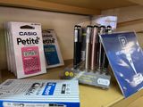 many different pens and pens on a shelf next to a calculator and a calculator