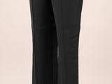 La femme porte un haut blanc et un pantalon noir.