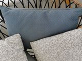 three pillows on a wicker chair in front of a yellow striped wall