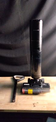 un objet noir posé sur une table en bois, avec une paire de ciseaux à côté