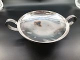a silver bowl with a handle sitting on a table