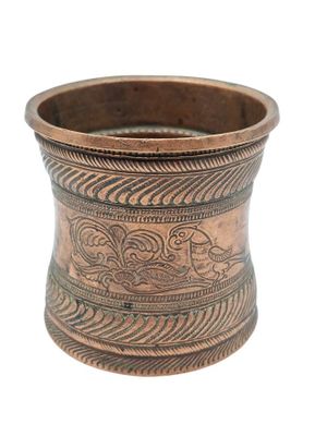 une vieille tasse en cuivre ornée d'un motif sur le côté