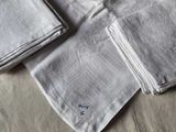 three folded napkins on a bed with a monogrammed design
