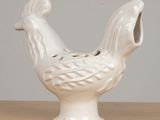 a white ceramic chicken that is sitting on a table