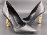 black leather pumps with gold heelings on a grey surface