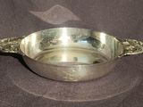 a silver bowl with a handle on a table