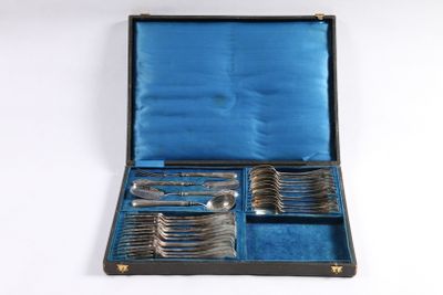 des couverts dans un coffret posé sur une surface blanche avec un fond bleu