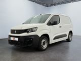 La camionnette blanche est garée dans une grande pièce au sol gris.