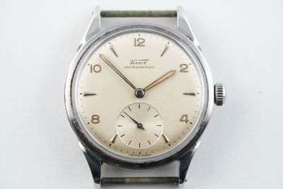 l'image d'une montre avec un bracelet vert sur une surface blanche