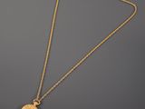 a gold plated necklace with a coin on a chain