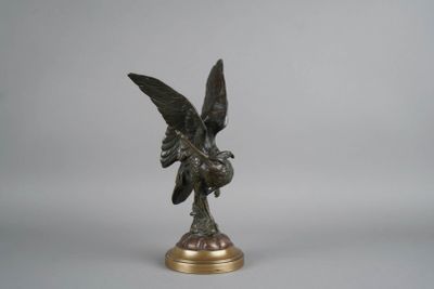 statue en bronze représentant un oiseau sur un socle, sur fond gris