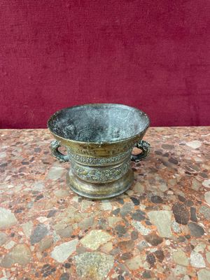 a small metal bowl on a table with a red background