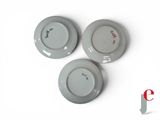 three gray plates with red writing on them sitting on a white surface