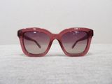 purple sunglasses on a white surface with a white wall in the background