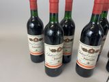 four bottles of red wine are lined up on a counter