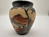 a vase with a painting on it sitting on a table
