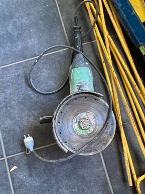 une perceuse posée par terre à côté d'une pile d'outils