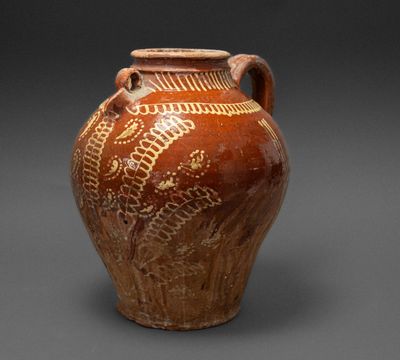 a brown vase with designs on it on a gray surface