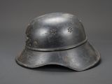 an old helmet with holes on the side of it on a gray surface