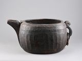 a black pot with a handle on a white surface
