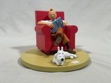 figurine of a man sitting in a chair reading a book with a dog laying on the floor