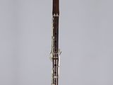 a silver and wood flute on a stand with a white background