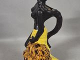 yellow and black figurine of a woman with a flower in her hand