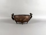 an old bronze bowl with two birds on it on a white surface
