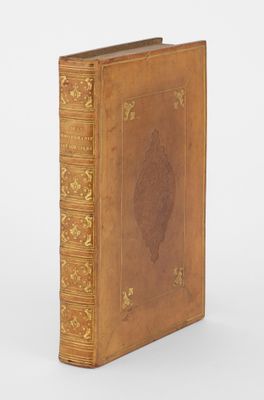 un vieux livre à la couverture dorée, ornée d'un motif raffiné sur la page de garde