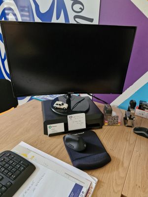 a desk with a computer monitor, keyboard, mouse, and other items on it