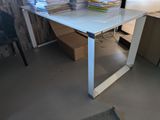 une table en verre sur laquelle est posée une pile de livres