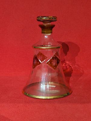 une bouteille en verre avec un bouchon doré sur fond rouge